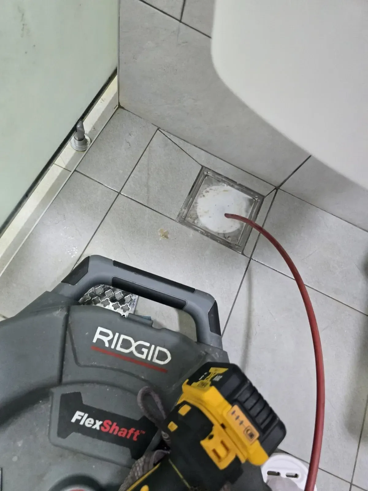 욕실 바닥 배수구에 관통기 와이어를 넣어 뚫는 작업